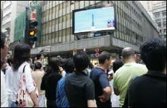 People watch the launching of China\'s second manned space mission in Hong Kong