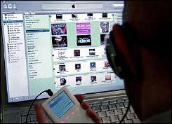 A man holds an iPod as he browses through the iTunes music store online