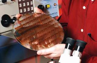 Professor John Cressler is reflected in a 200 GHz silicon-germanium integrated circuit wafer.
