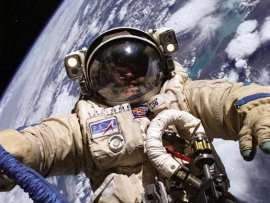 ISS astronaut Mike Finke spacewalks in a Russian Orlan spacesuit in 2004. SuitSat will have no one inside.