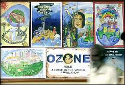 A man (R) walks past a display of paintings by students for the preservation of the ozone layer