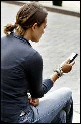 A woman uses her mobile phone to send an SMS text message