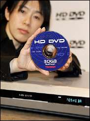A Toshiba employee displays the prototype model of the HD DVD player and its 30GB disc