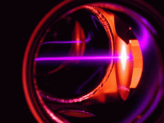 An Er beam emerging from a hot oven (orange glow on right) being slowed by a violet laser beam