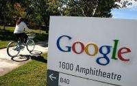 A Google employee rides a bicycle by a sign at the company's headquarters
