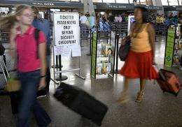 Airline travelers pull their carry-on luggage into the fast-moving security check lane in 2006