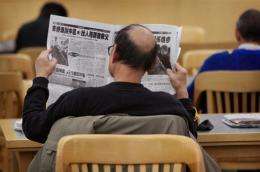 A man reads a Chinese language newspaper at a library in Chicago, Illinois
