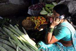 An Indian vendor uses her mobile phone to take customers orders