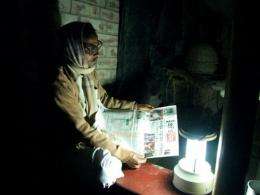 An Indian villager is seen reading a newspaper with the aid of a solar powered lamp