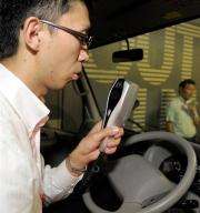 A Toyota Motors engineer blows into the hand-held breathalyser and camera unit