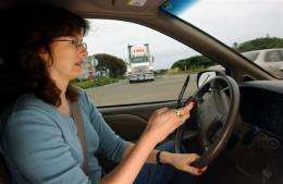 A woman dials a cell phone while driving in California in 2003.