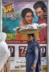 A woman walks in front of a mobile phone company advertisement in Islamabad