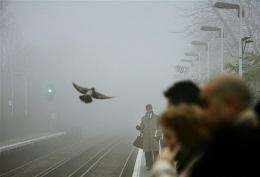 Commuters wait on the platform shrouded by fog in London