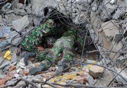 Indonesian soldiers crawl under a collapsed building during a rescue attempt in the Sumatran city of Padang