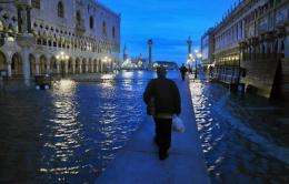 People walk on a plateform on the flooded Piazza San Marco (St Mark's square) in Venice