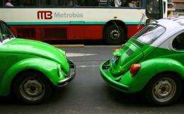 Two vintage beetle Volkswagen taxies pass by a  new "Metrobus" in Mexico City