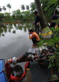 Vietnamese and foreign technicians work at a lake inside the presidential palace in Hanoi