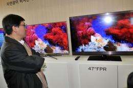 A journalist compares the competing 3-D televisions of Samsung(L) and LG(R)