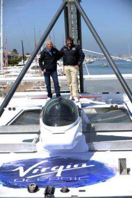 Sir Richard Branson (L) and explorer Chris Welsh stand above a tiny Virgin submarine