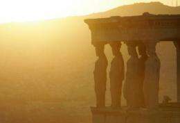 The sun sets behind replicas of the Caryatids on Erechtheion temple on the Acropolis Hll in Athens