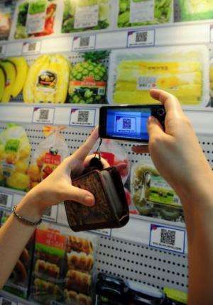 A South Korean woman uses her smartphone to buy a product at the virtual retail shop at Seolleung subway station in Seoul