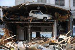 A car remains stuck under the roof of a warehouse, after it was pushed there by the recent tsunami