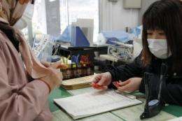 A civic official hands potassium iodide tablets to a woman at a civic building in Iwaki, Japan, in March