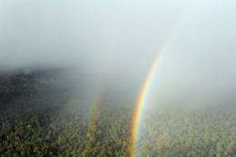 A double rainbow shines thru the rain over the forest in West Kalimantan