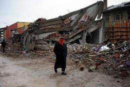 A homeless survivor walks by a collapsed building after an earthquake in Ercis, Turkey