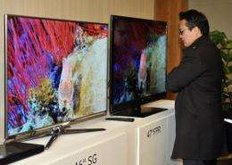 A journalist compares the 3-D televisions of Samsung(L) and LG(C) in Seol