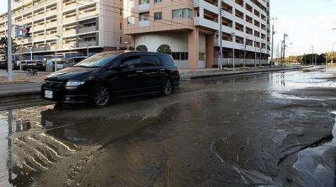 A lone car rests among the remain of water on a street in Chiba city