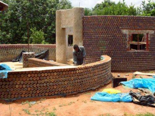 A man builds a wall with plastic bottles in the village of Sabon Yelwa