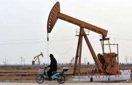 A man riding his scooter ride past oil rigs in Cangzhou, in northern China's Hebei Province, near Bohai Bay, in 2009