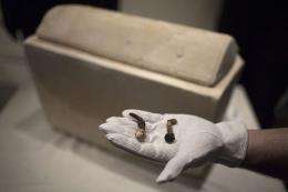 A man shows two Roman nails next to a Roman period ossuary
