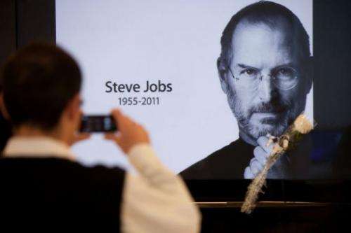 A man takes a picture of a portrait of Steve Jobs