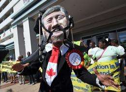 An activist wears a mask depicting the face of Canadian Prime Minister Stephen Harper during a protest in Durban