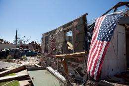 An American flag hangs off a destroyed house