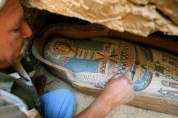 An Egyptian worker brushes the dust off a coffin containing mummy found at Lahun, southwest of Cairo,