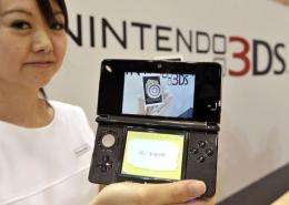 A Nintendo employee displays a portable videogame console with a 3D display called the "Nintendo 3DS"