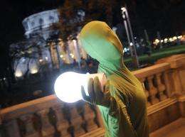 A performer wearing a green outfit displays an electric bulb-shaped lantern in Romania