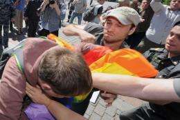 A Russian policeman (R) tries to stop a man (C) hitting a gay rights activist in central Moscow on May 28