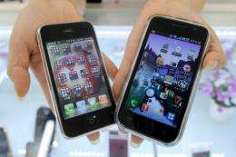 A South Korea shop manager shows Samsung Electronics' Galaxy S mobile phone (R) and Apple's iPhone 3G (L)