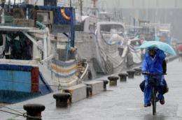A Taiwanese fish worker rides past the Nanfangauo harbor as typhoon Songda approaches