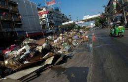 A vehicle drives past a garbage pile in a road in Bangkok following the floods