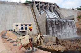 A worker carries empty cement bags across the front of the Kamchay dam at today's inauguration ceremony