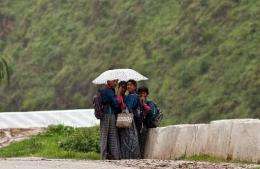Bhutanese schoolgirls take shelter under an umbrella during heavy rainfall