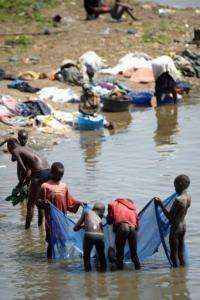 Boys use a net to fish while women wash clothes in the banks of the White Nile River