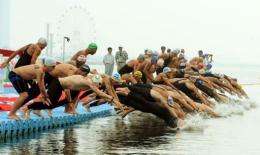 Competitors dive at the start of the men's 10km open water swimming event
