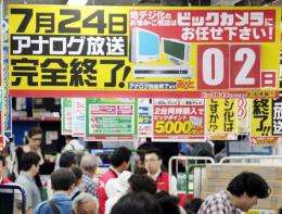 Consumers walk by a sign informing customers that two days remain before the country will end analog broadcasts