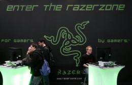Fairgoers play video games in front of the stand of gaming peripherals producer "Razer"